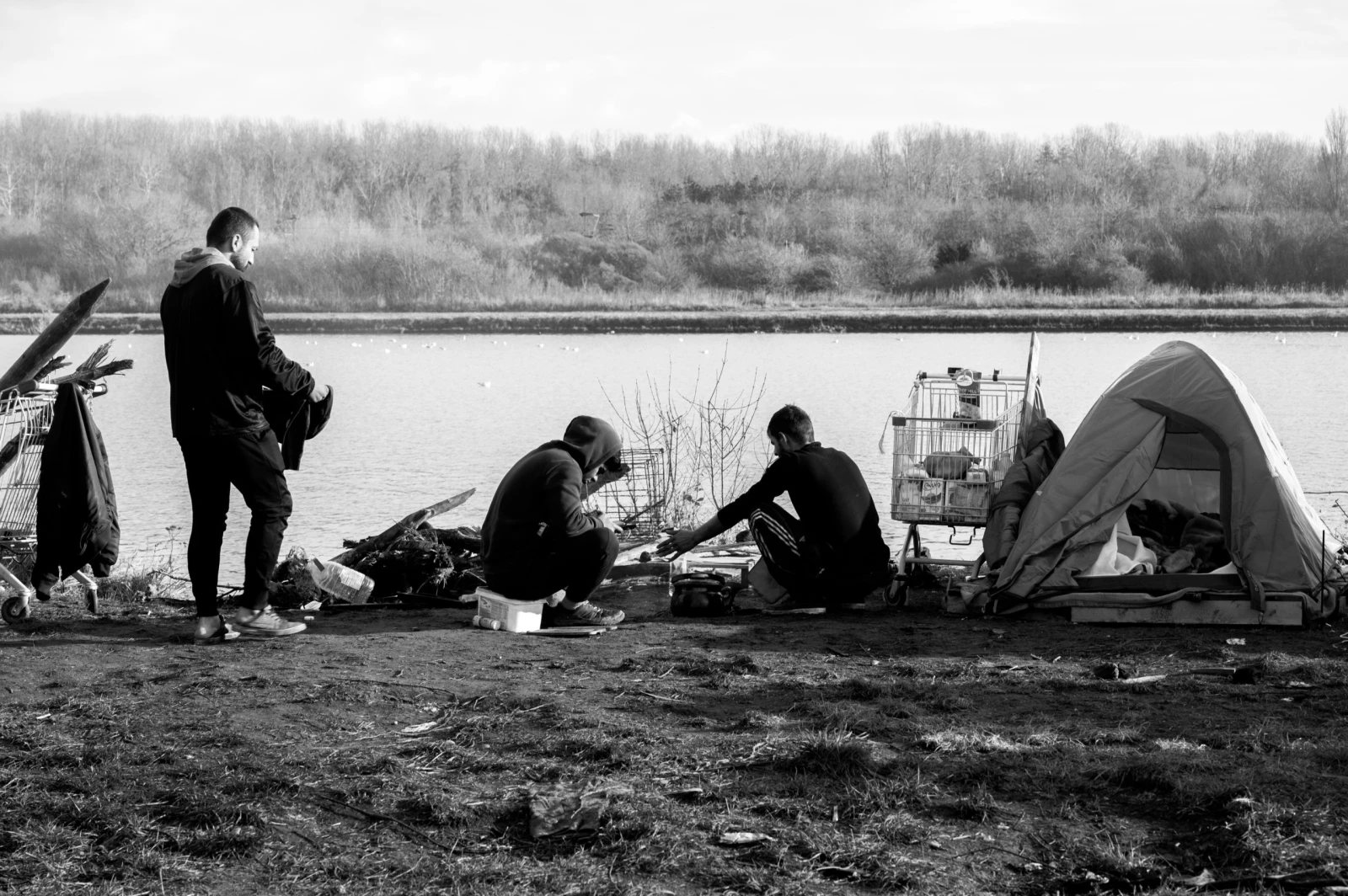 Trois jeunes hommes. Ils passent le temps comme ils peuvent, à proximité de leur campement à Grande-Synthe.